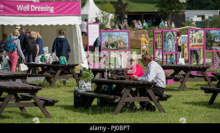 I visitatori guardano tondo come giovane seduto al tavolo da picnic sono drink & chat dalla medicazione e display - RHS Chatsworth Flower Show, Derbyshire, England, Regno Unito Foto Stock