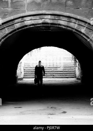 Imprenditore a piedi attraverso un sottopassaggio nel Central Park di New York Foto Stock