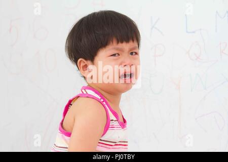 Little Boy a piangere sul muro a secco di sfondo, Foto Stock