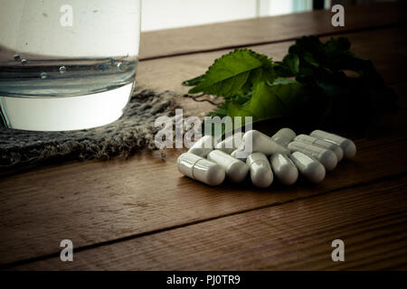 Medicina alternativa compresse su una tavola di legno, foglia verde. Foto Stock