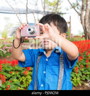 Little Boy asiatici prendere la fotocamera sul fiore giardino, Foto Stock