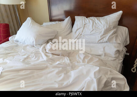 Confuso disfatto hotel letto in una stanza di un hotel. Fogli bianchi, che necessita di un servizio di pulizie Foto Stock