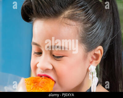 Carino bambina di mangiare il delizioso fritto di pollo Foto Stock