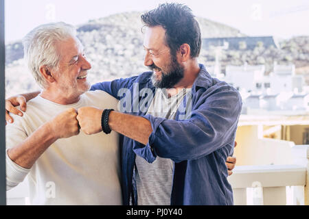 Due maschi felici amici padre e figlio avente un buon tempo insieme dando friendly punch vicenda. città e sulle montagne sullo sfondo. popolazione caucasica Foto Stock