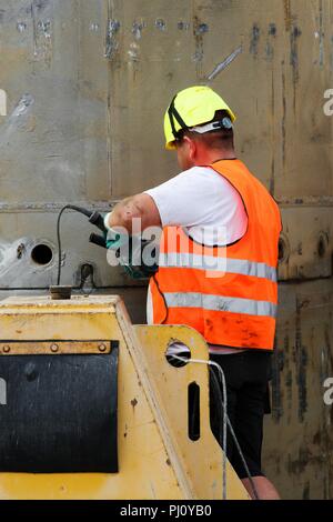 Lavoratore con un casco giallo e arancio un giubbotto di sicurezza Foto Stock