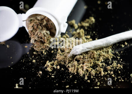 La marijuana medica la fuoriuscita di una prescrizione di bianco bottiglia con un giunto su sfondo nero. Foto Stock