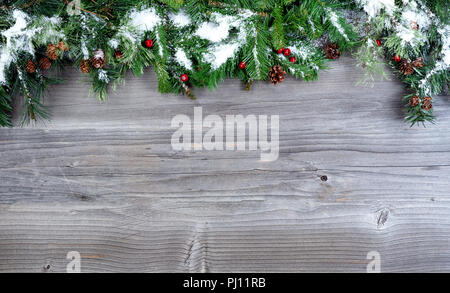 Coperta di neve albero di Natale rami sempreverdi posto sulla sommità di un rustico sfondo di legno Foto Stock