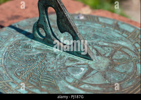 Avvicinando 5pm per andare a casa come registrato su un ottone meridiana spiovente rivestito in patina con gnomone ombra sul quadrante e regolazione del sole Foto Stock