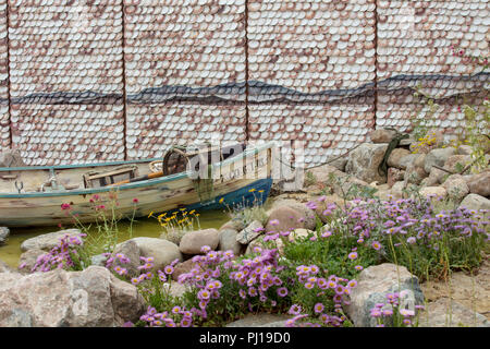 RHS Hampton Court Flower Show 2018, Show Garden che rappresenta una baia isolata galiziana, rivestimento di conchiglie tradizionale, barca rustica e pod di aragosta. Foto Stock