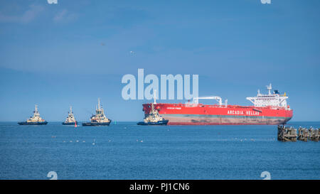 Il grezzo petroliera Mar Egeo potenza con una portata lorda di progetto di 115,754 tonnellate viene portato nella guarnizione Sands port da quattro rimorchiatori. Foto Stock