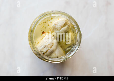 Decapare i cuori di carciofo Pickle in una bottiglia di vetro Jar. Alimenti biologici. Foto Stock