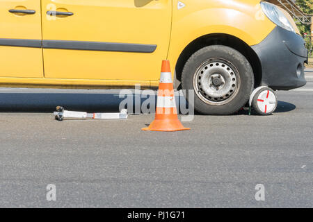 Close-up di uno scooter su un attraversamento pedonale. Il problema della sicurezza dei bambini sulla strada. Parti di scooter elettrico sotto le ruote della macchina. auto Foto Stock