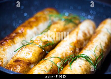 A pochi fritti, freschi e fragranti salsicce, giacciono su un nero padella e friggere. Sono decorate con freschi e aneto utili. Molto gustoso cibo da natur Foto Stock