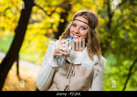 Bella ragazza boho gode di acqua potabile nel parco. Foto Stock