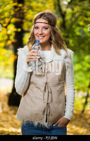 Bella ragazza boho gode di acqua potabile nel parco. Foto Stock