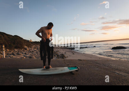 Surfer indossando il costume sulla spiaggia Foto Stock