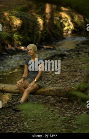 Donna relax su log in legno Foto Stock