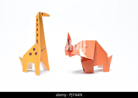 Un rosso elefante origami stand con un giallo giraffa origami su sfondo bianco Foto Stock