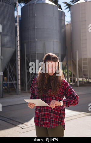 Lavoratore di sesso femminile che controllando il tempo mentre usando tavoletta digitale Foto Stock Lavoratore di sesso femminile che controllando il tempo mentre usando tavoletta digitale Foto Stock