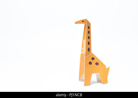 Un giallo origami giraffe si eleva alto su sfondo bianco Foto Stock
