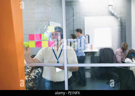 Executive maschio guardando sticky notes Foto Stock