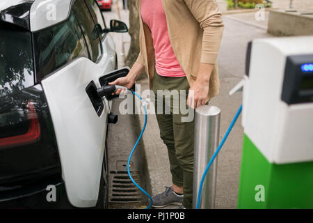 Uomo di ricarica auto elettrica Foto Stock