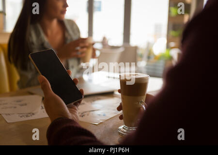 Uomo che utilizza un cellulare in cafe Foto Stock