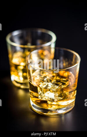 Bicchiere di bibita alcolica con cubetti di ghiaccio sulla tavola nera. Whiskey in vetro.