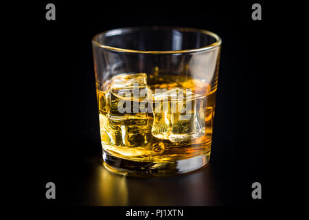 Bicchiere di bibita alcolica con cubetti di ghiaccio sulla tavola nera. Whiskey in vetro. Foto Stock