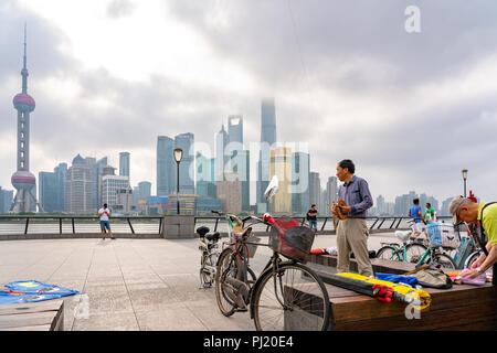 Uomini anziani preparare i loro corredi di volare su un inizio di mattina lungo il Bund a Shanghai in Cina. Foto Stock