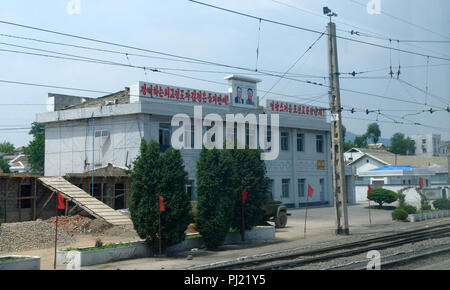 Stazione ferroviaria edificio di grandi dimensioni con i ritratti di Kim Il Sung e Kim Jong Il su di esso. Foto Stock