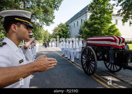 Aspiranti guardiamarina salutate come bandiera drappeggiati scrigno di John McCain come a cavallo il cassettone processi per l'Accademia Navale degli Stati Uniti cimitero per il suo servizio di sepoltura il 2 settembre 2018 in Annapolis, Maryland. John S. McCain, III si è laureato dall'Accademia Navale degli Stati Uniti in 1958. Egli è stato un pilota della marina degli Stati Uniti, un prigioniero di guerra nel Vietnam, i membri del Congresso degli Stati Uniti e il senatore e due volte candidato presidenziale. Ha ricevuto numerosi premi, tra cui la stella d'argento, legione di merito, cuore viola e Distinguished Flying Cross. Foto Stock