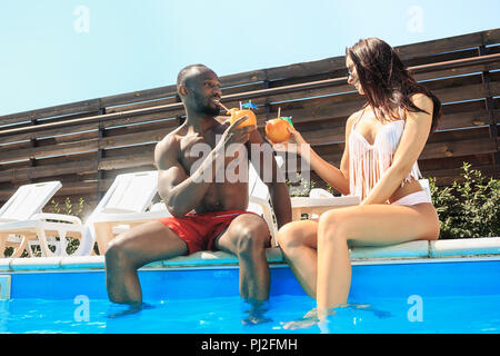 L Africano l uomo e la donna come amici di giocare e rilassarsi in una piscina durante le vacanze estive. Le persone felici divertendosi in piscina. Tempo libero, nuoto, estate, ricreazione, sano concetto lifstyle Foto Stock