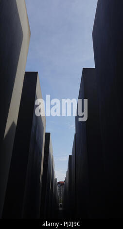 Blue sky attraverso un percorso nel Memoriale dell Olocausto, Berlino, fatta di alti blocchi in calcestruzzo Foto Stock