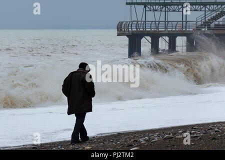Drammatico, tempeste, mare spiaggia con grandi onde, singolo, lonely vecchio uomo a camminare lungo la costa, vista posteriore. Concetto di solitudine, anima-la ricerca. Foto Stock
