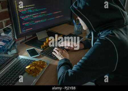 Hacker facendo bitcoin rapina virus malware thru. con una pila di bitcoin intorno al tavolo. concetto di reati economici. Foto Stock