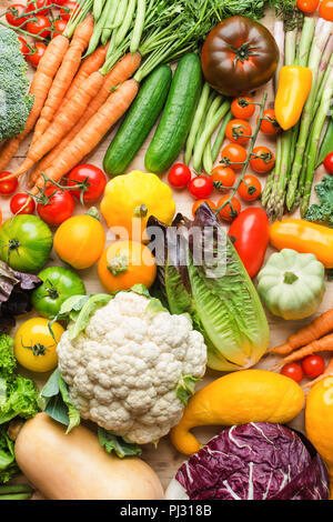 Assortimento di coloratissimi fresche verdure organiche su legno tabella di pino, cibo crudo sfondo, vista dall'alto, verticale, il fuoco selettivo Foto Stock