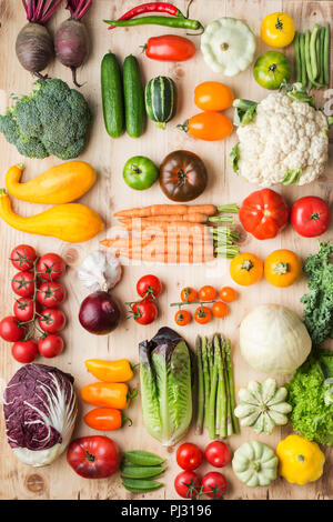 Assortimento di coloratissimi fresche verdure organiche su legno tabella di pino, cucina creativa lo sfondo in una griglia, verticale, vista dall'alto, il fuoco selettivo Foto Stock