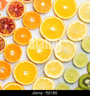 Diverse varietà di agrumi, le arance, i limoni e limette, kiwi disposti in righe diagonali, square. Sfondo colorato, vista dall'alto Foto Stock