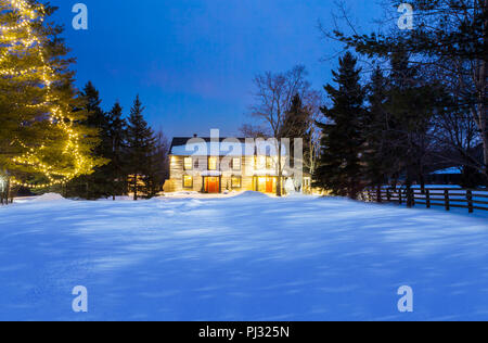 Casa log in una notte d'inverno con le luci accese Foto Stock
