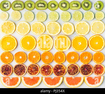Fette di frutta ricca di vitamina C, Arance, Limoni Limette Mandarini Satsuma, kiwi, pompelmi disposti in righe. Sfondo colorato, vista dall'alto Foto Stock