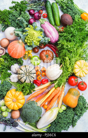 Prodotti freschi di fattoria, varieity di coloratissimi biologica di verdure ed erbe aromatiche su pietra grigio chiaro sfondo, vista dall'alto, il fuoco selettivo Foto Stock