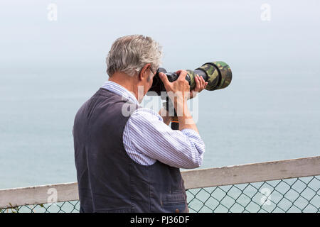 Fotografo tenere la fotocamera con lente camuffato prendendo foto a Bournemouth Air Festival, Bournemouth Dorset Regno Unito nel mese di agosto Foto Stock