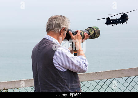 Fotografo tenere la fotocamera con lente camuffato prendendo foto a Bournemouth Air Festival con la chinook in cielo, Bournemouth Dorset Regno Unito nel mese di agosto Foto Stock