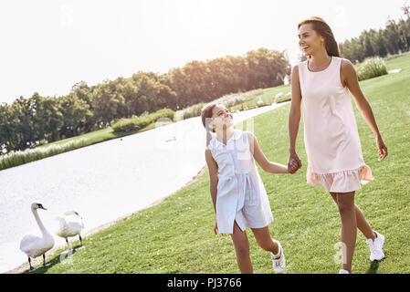 Genitore Single, madre e figlia camminando su un campo erboso hol Foto Stock