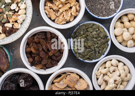 Ingredienti per in casa paleo granola, diverse le noci e l'uvetta, date, il seme sulla pietra grigia sfondo, vista dall'alto Foto Stock