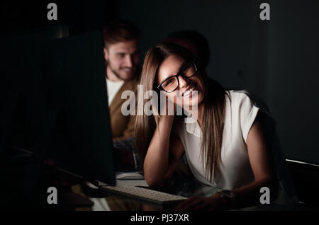 Young business woman seduto alla sua scrivania di notte Foto Stock