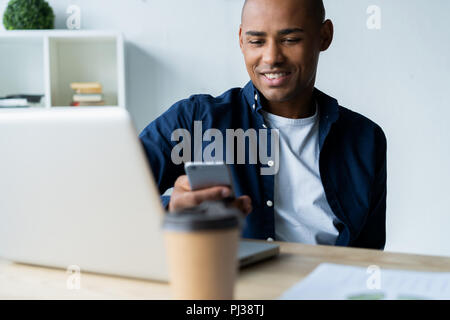 Felice African American businessman utilizzando un telefono cellulare in un ufficio. Foto Stock