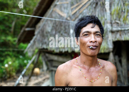 Ritratto di un uomo cordiale Mentawai che fuma di fronte alla casa, Sumatra, Siberut, indonesia Foto Stock