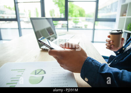 Felice African American businessman utilizzando un telefono cellulare in un ufficio. Foto Stock